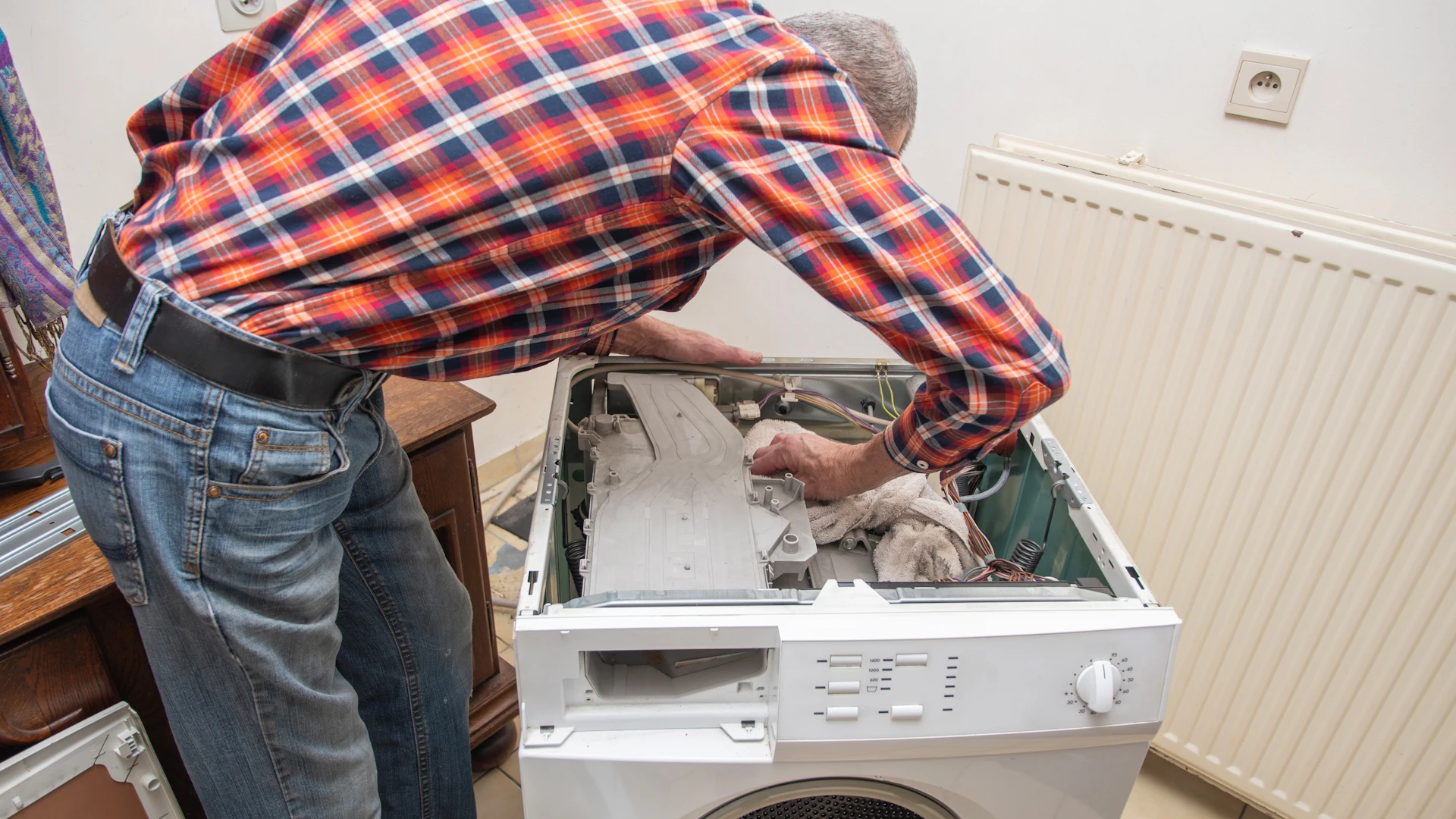Mies korjaa pyykinpesukonetta.