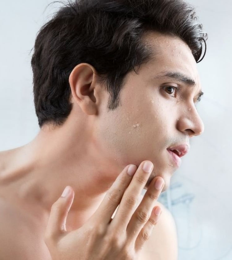 Ένας άντρας κοιτάζει τον εαυτό του στον καθρέφτη αφού ξύρισε τα γένια του με το ξυράφι Gillette