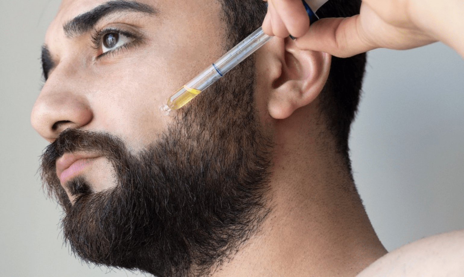 Un uomo usa un olio per barba ammorbidente sul suo viso