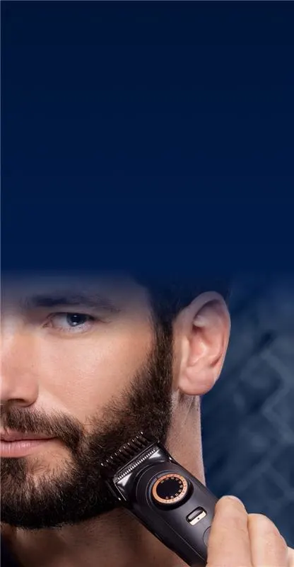 Homem a aparar a barba com máquina elétrica contra fundo azul escuro