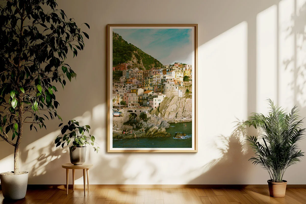 Framed picture of a coastal town with colorful houses on a hill, hanging on a wall in the living room.
