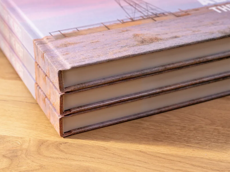 Gros plan sur un livre relié en lin avec une couverture imprimée et un autocollant vert indiquant « NOUVELLE RELIURE AVEC COUVERTURE IMPRIMÉE EN LIN ».