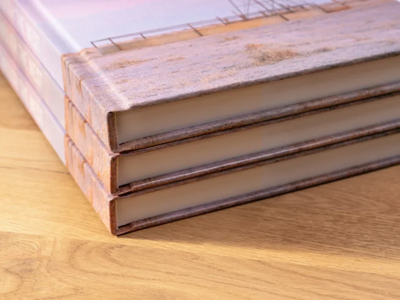 Gros plan sur un livre relié en lin avec une couverture imprimée et un autocollant vert indiquant « NOUVELLE RELIURE AVEC COUVERTURE IMPRIMÉE EN LIN ».