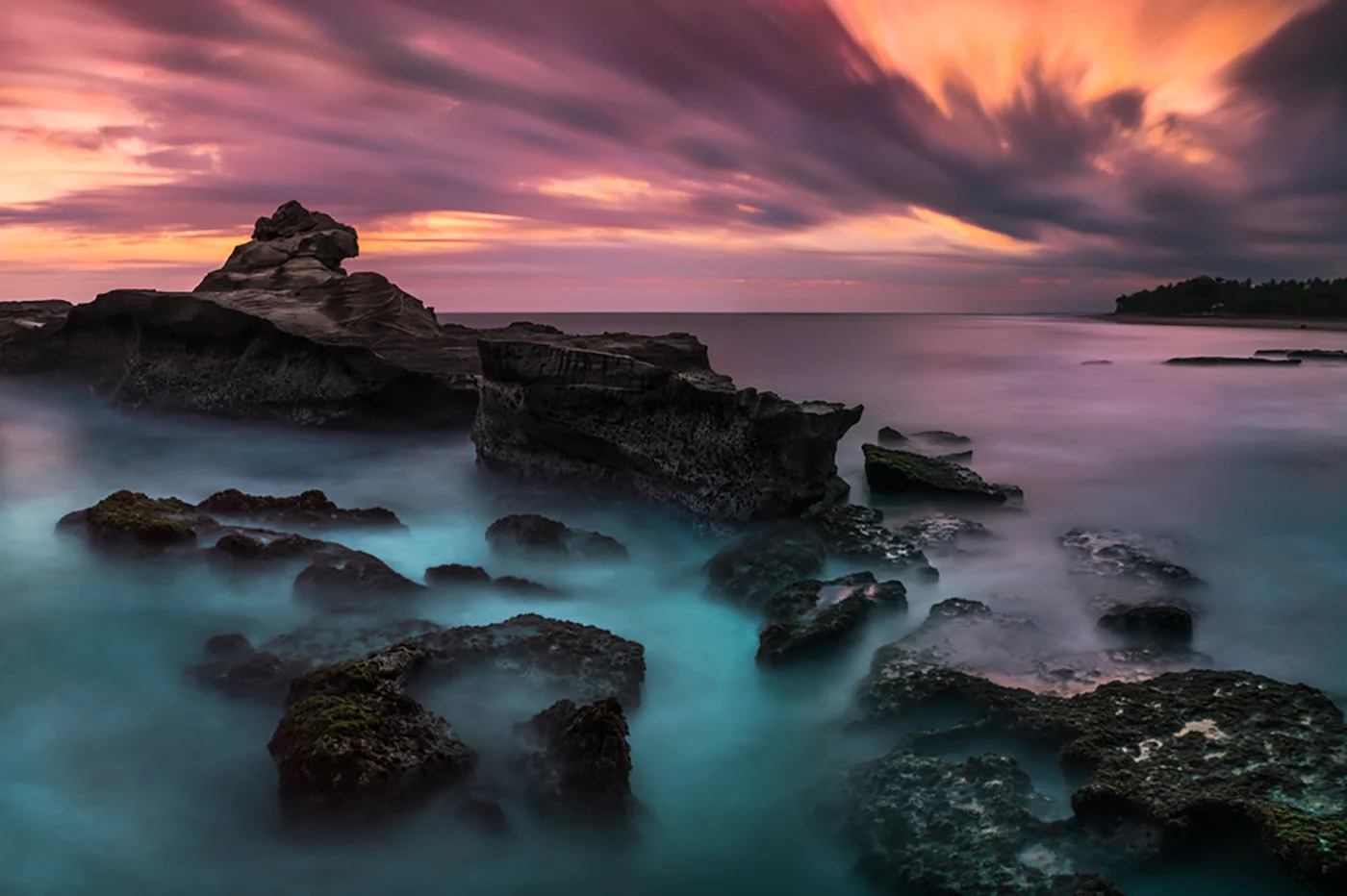 Rocky coastline with calm waters and dramatic sunset skies.