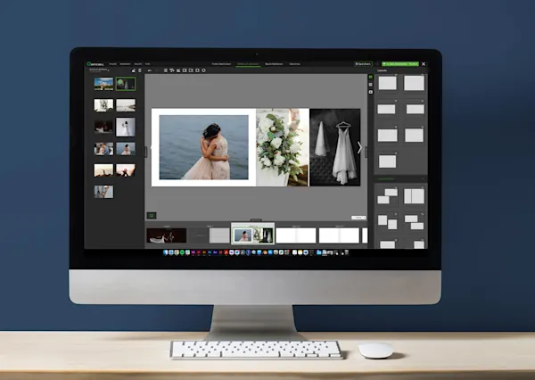 Computer screen displaying wedding photo book software with thumbnails and a large preview image, on a clean wooden desk setup.