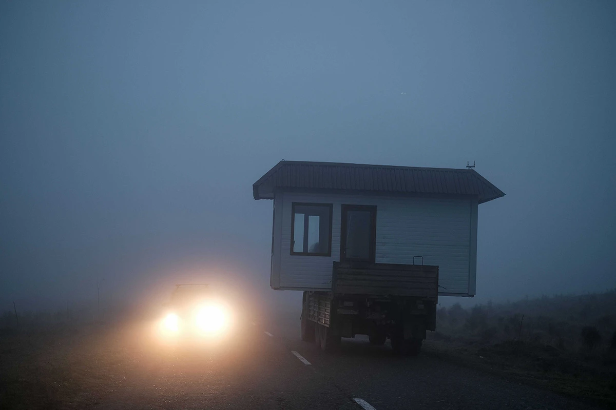 Cargo vehicle with a shed on the trailer driving on a foggy road - photo by Areg Balayan.
