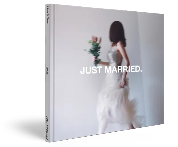 Hochzeitsfotobuch mit glänzendem Hardcover, das eine verschwommene Braut in weißem Kleid mit Blumenstrauß zeigt, darüber der Text "JUST MARRIED." in fetten schwarzen Buchstaben