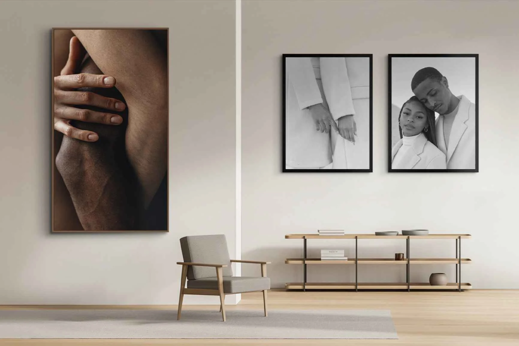 Soggiorno con poltrona, scaffale e tre fotografie incorniciate appese alla parete, tra cui un primo piano di due mani e due ritratti in bianco e nero.