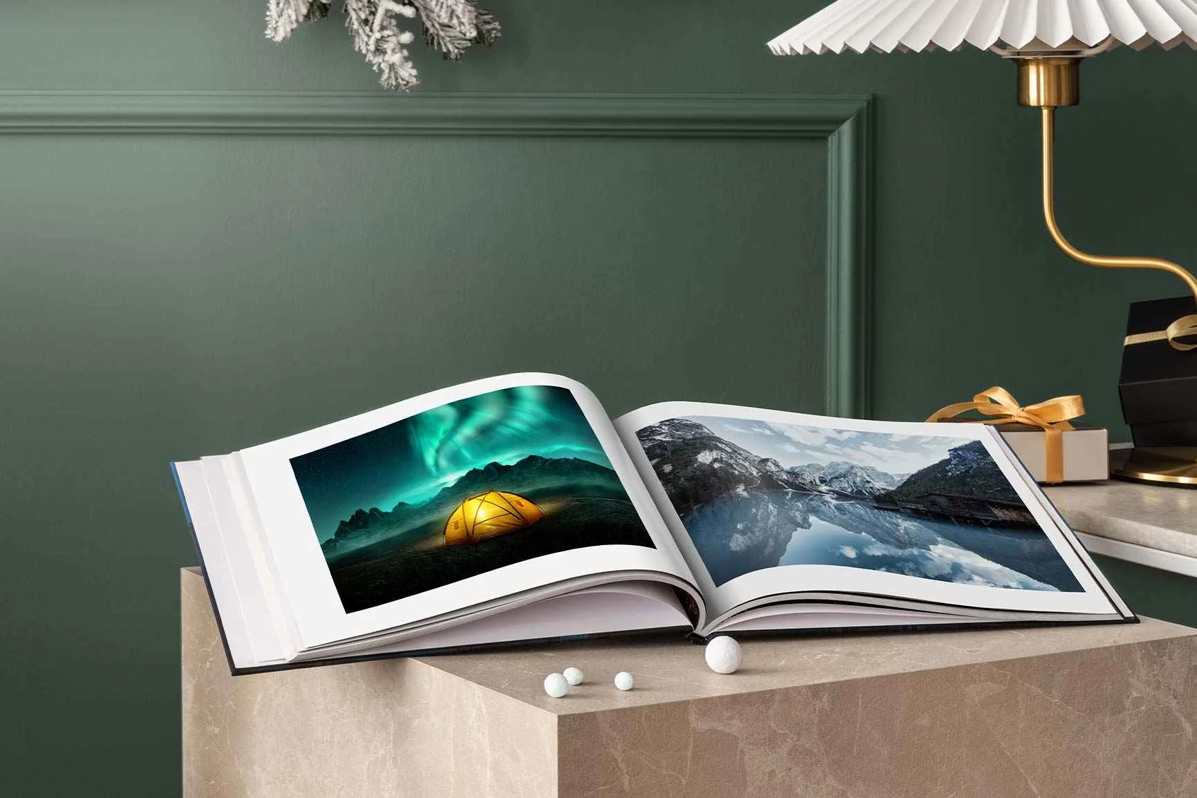 Aufgeschlagener Bildband mit Fotos von einem Zelt unter Nordlichtern und einer Berglandschaft, auf einem Tisch vor grünem Wandpaneel.
