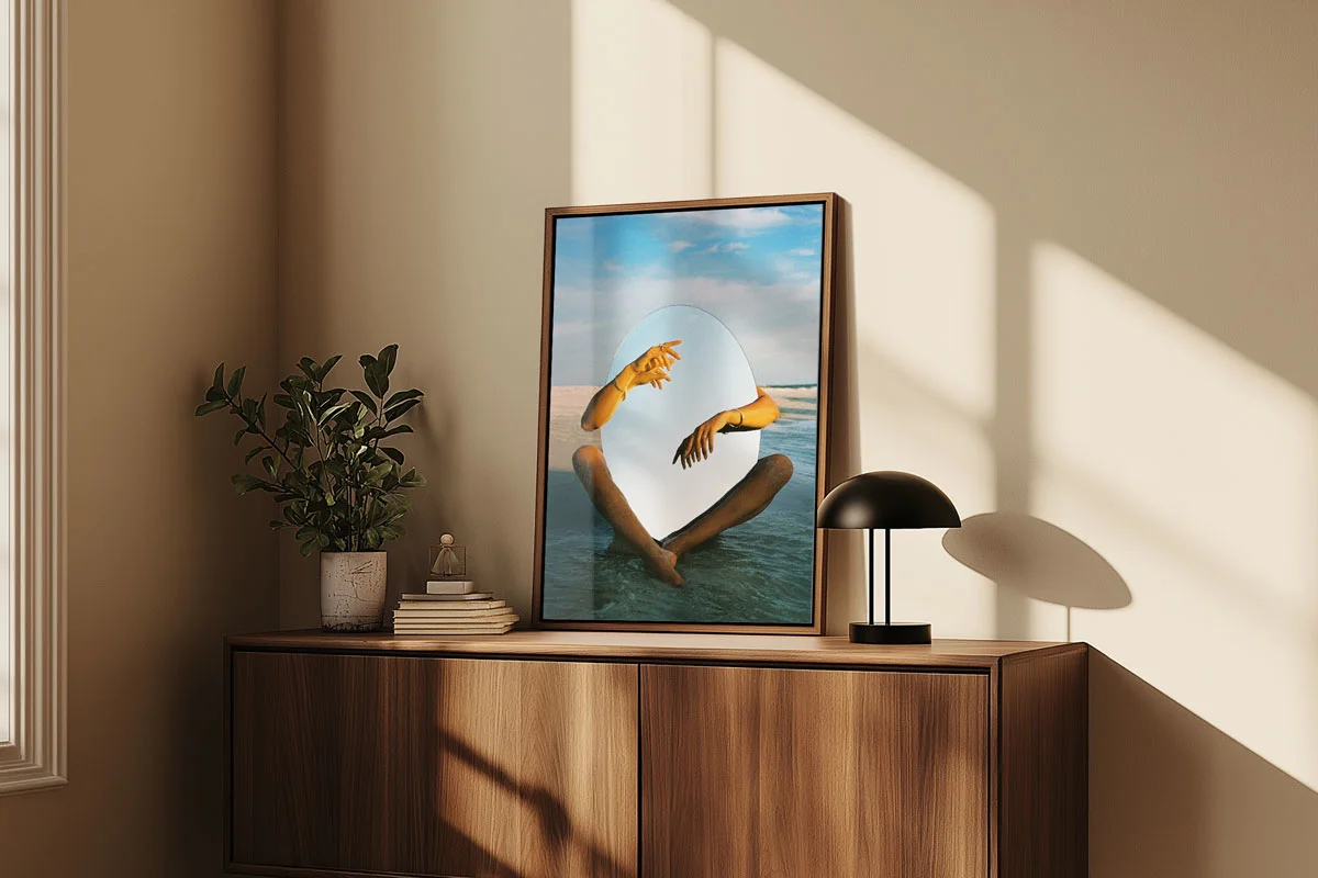 Framed picture with surreal depiction of hands and mirror above modern wooden cabinet.