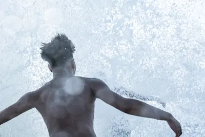 Young man throwing himself off a cliff into the sea.