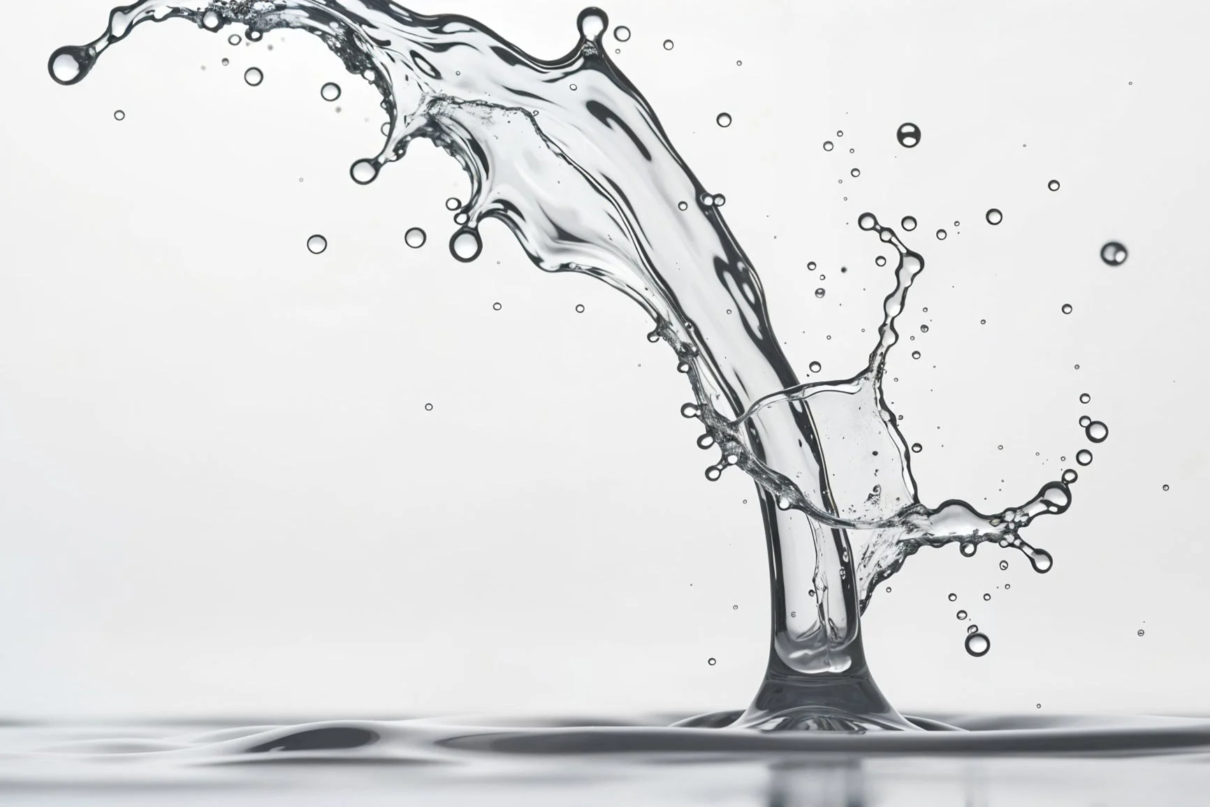 A water droplet hits the water's surface and creates a dynamic splash with several small droplets.