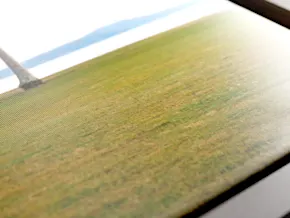 Gros plan d’une impression sur toile textile représentant une image d’un champ d’herbe verte sous un soleil éclatant, avec un ciel bleu.