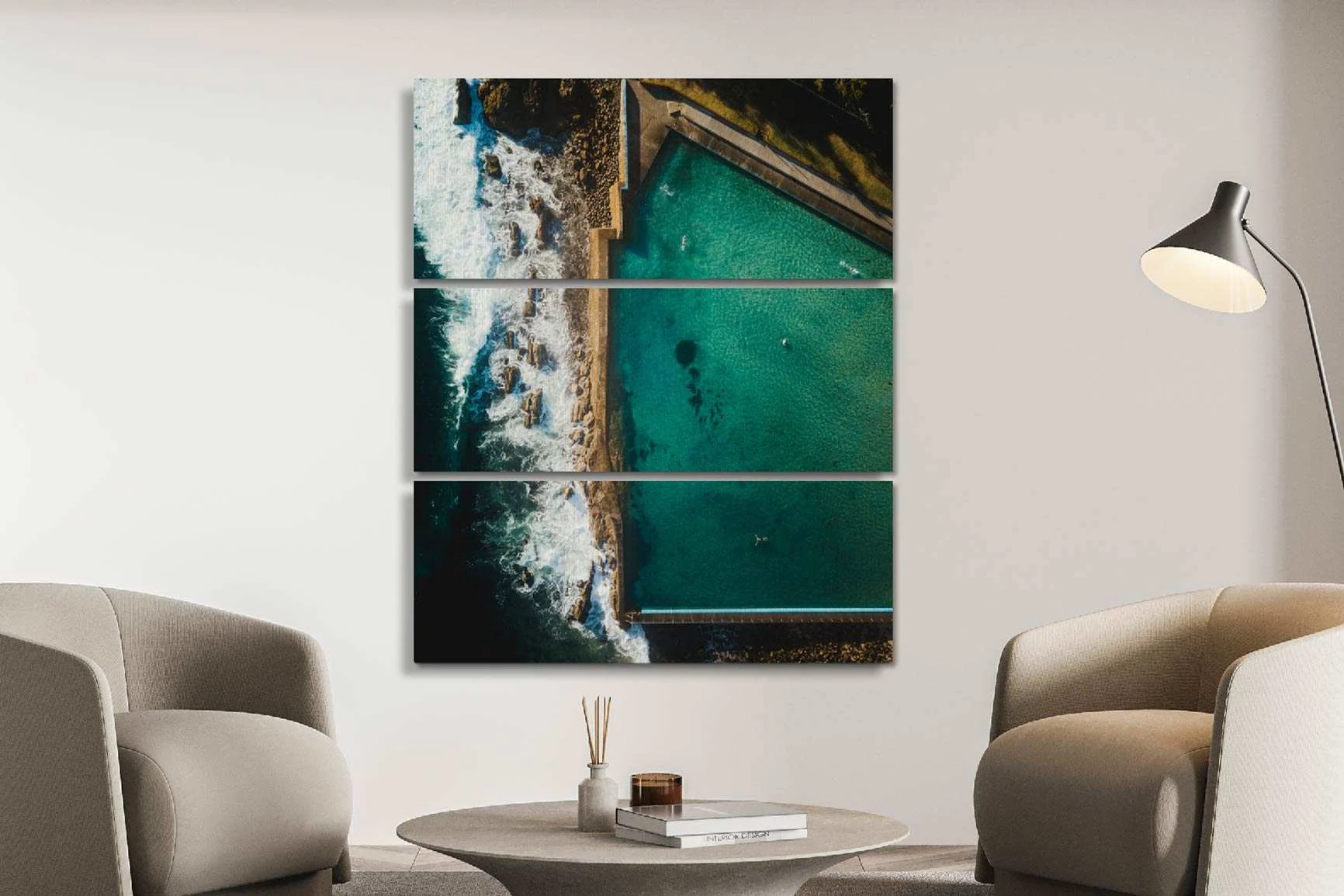 Trittico con veduta aerea di una baia su una costa rocciosa con onde e diversi nuotatori, appeso sopra un tavolino rotondo.