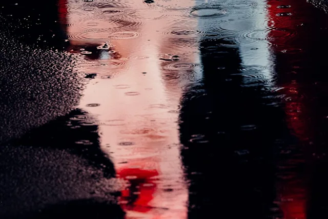 Verzerrtes Gesicht mit roten Lippen, reflektiert auf einer nassen Oberfläche.