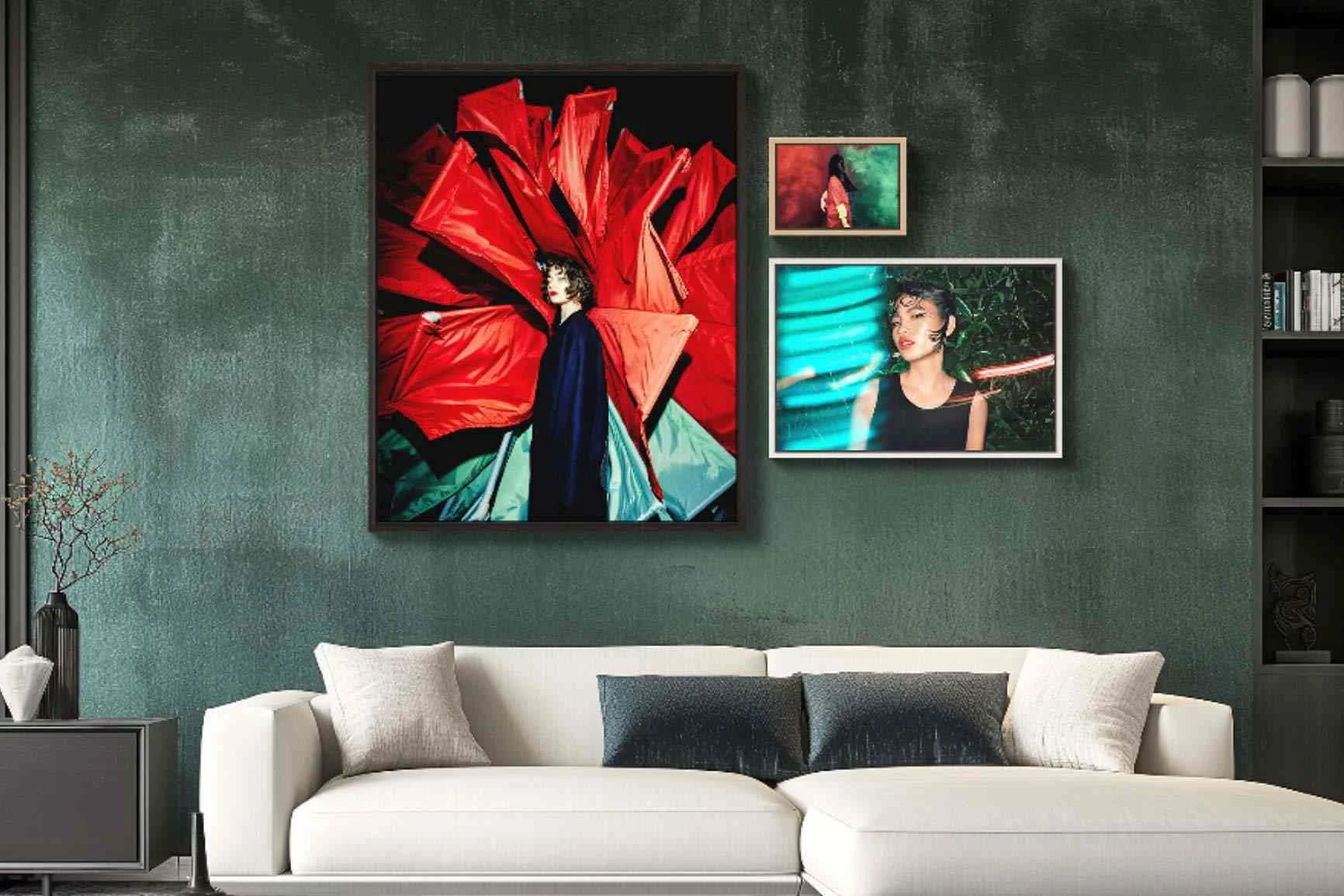 Soggiorno con divano bianco, cuscini e tre quadri incorniciati su una parete verde, tra cui un grande ritratto di una persona su sfondo rosso.