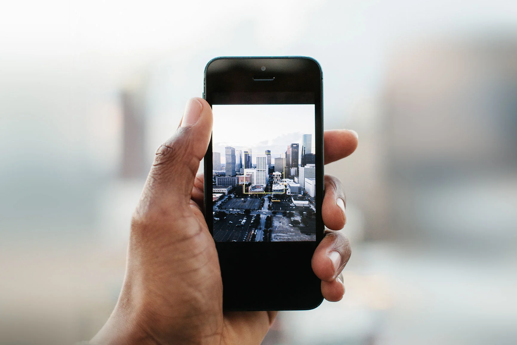 Mano sosteniendo un smartphone con una foto de una vista de la ciudad y rascacielos.