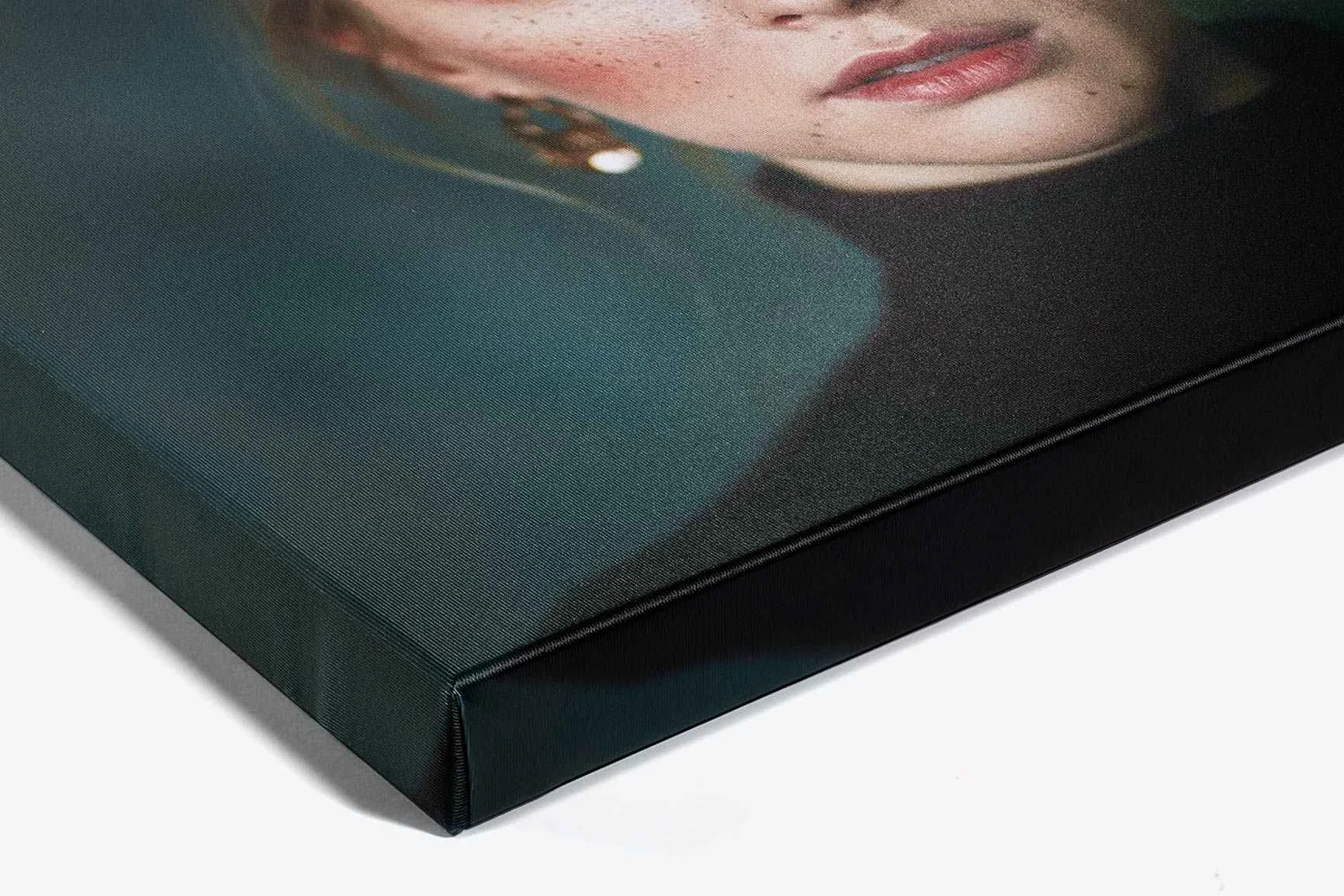 Nahaufnahme einer Ecke einer aufgespannten Leinwand mit einem Porträt einer Frau, die Ohrringe trägt.