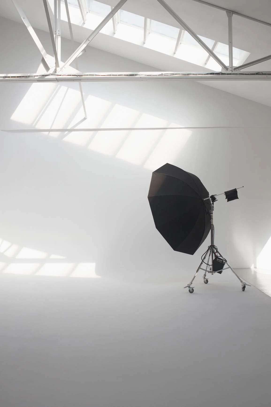 Photo studio with large black flash screen on a tripod and white background.