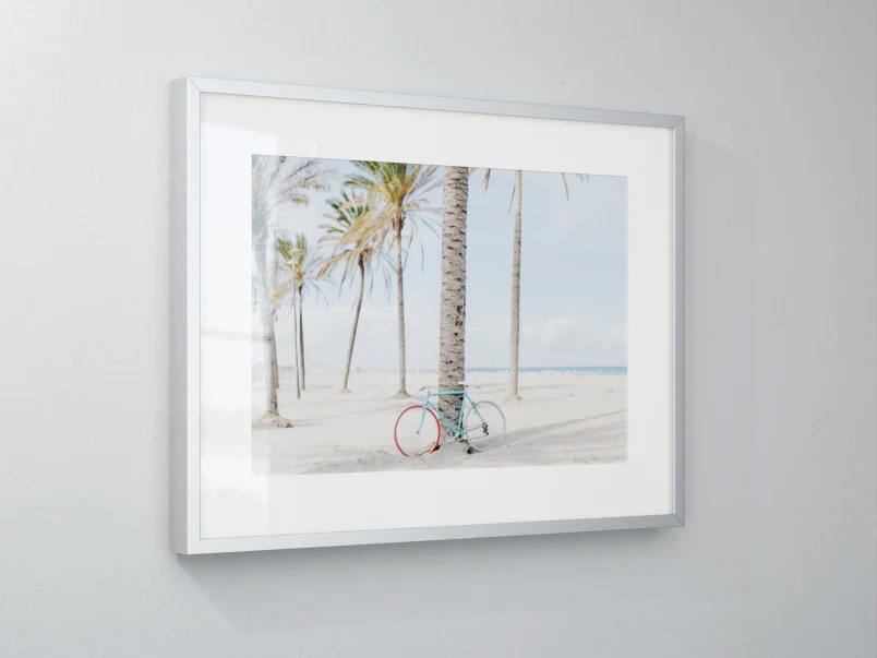 Grey wall with magnet framed fine art print. The picture shows a bike on a beach with palm trees.