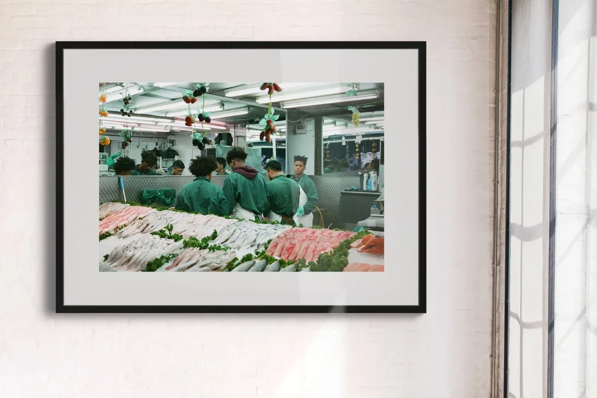 Four young men in green working clothes working behind a fresh fish counter.