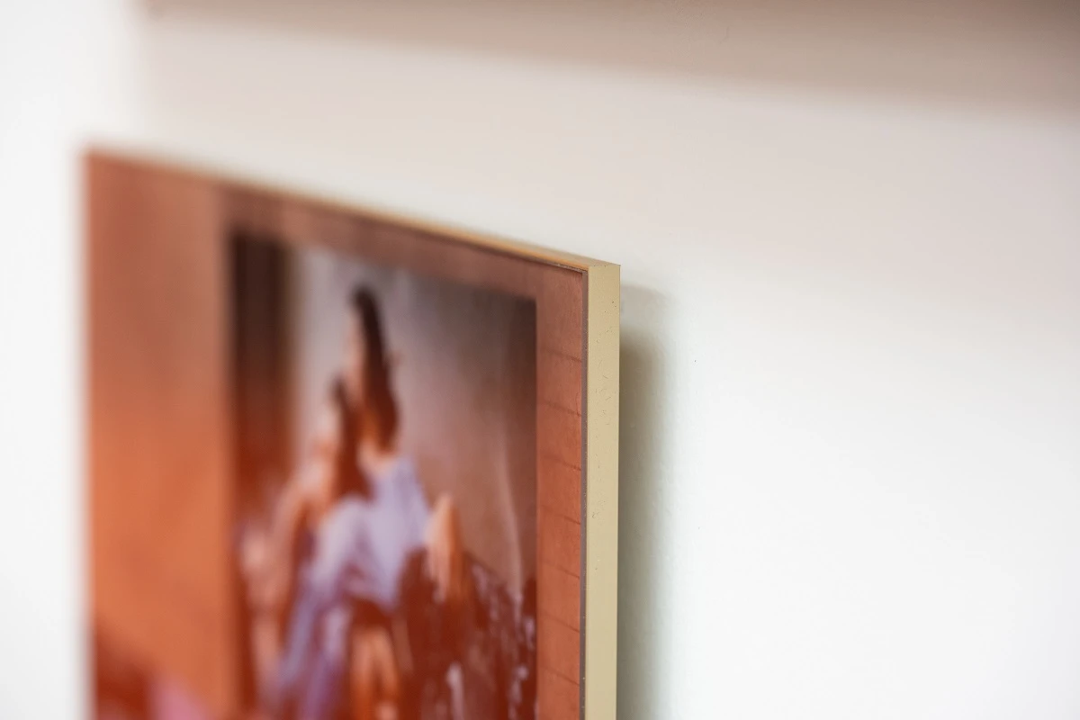 close up of a photo of the exhibition as an acrylic print in a golden slimline case.