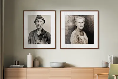 Two framed portrait photos on the wall, including a wooden chest of drawers with bowls, books and decorations.
