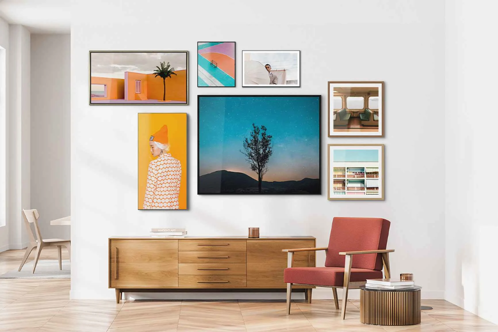 Soggiorno con credenza, poltrona rossa, tavolino e una parete con diverse immagini incorniciate di varie dimensioni.