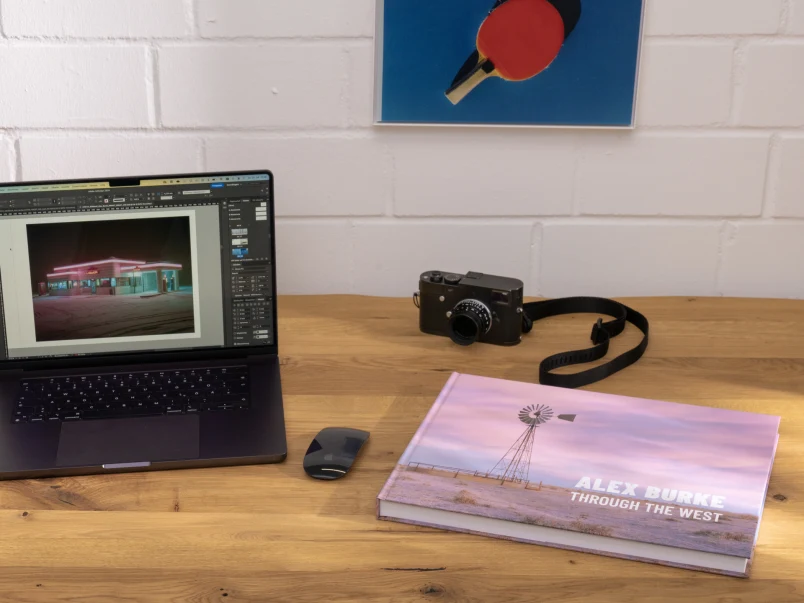 Closed coffee table book on work table next to laptop