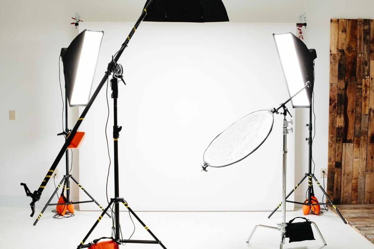Fotostudio met twee grote softbox-lampen, een reflector en een witte achtergrond.