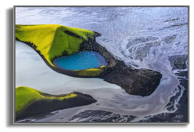 A picture of the frost melt in Iceland taken from above with a drone representing water and a little bit of green land in the middle of the water.
