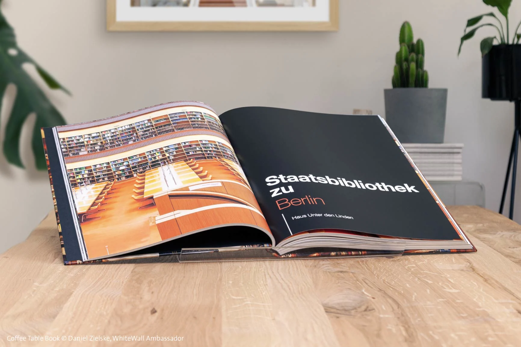 Aufgeschlagener Bildband mit Fotos der Staatsbibliothek zu Berlin auf einem Holztisch.