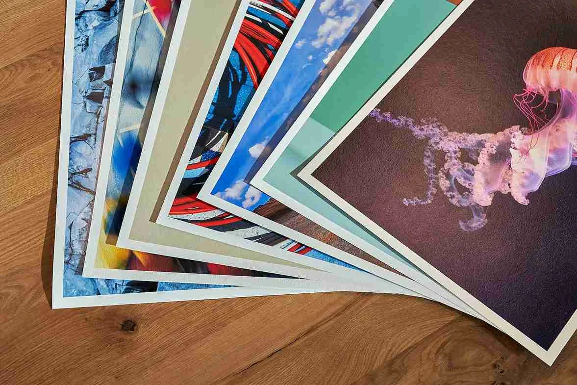 Mehrere Fine Art Prints sind auf einem Holztisch gestapelt.