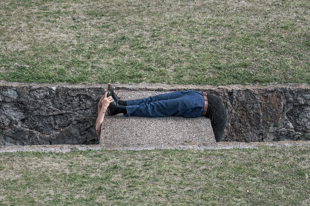 abstract photo of a person grabbing their own feet who is wrapped around a block of cement.