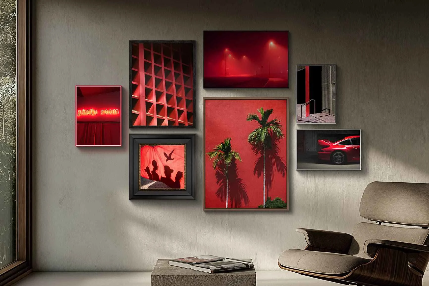 Wand mit sechs gerahmten Bildern in Rot- und Schwarztönen, darunter Palmen, ein Auto, Silhouetten und abstrakte Motive.