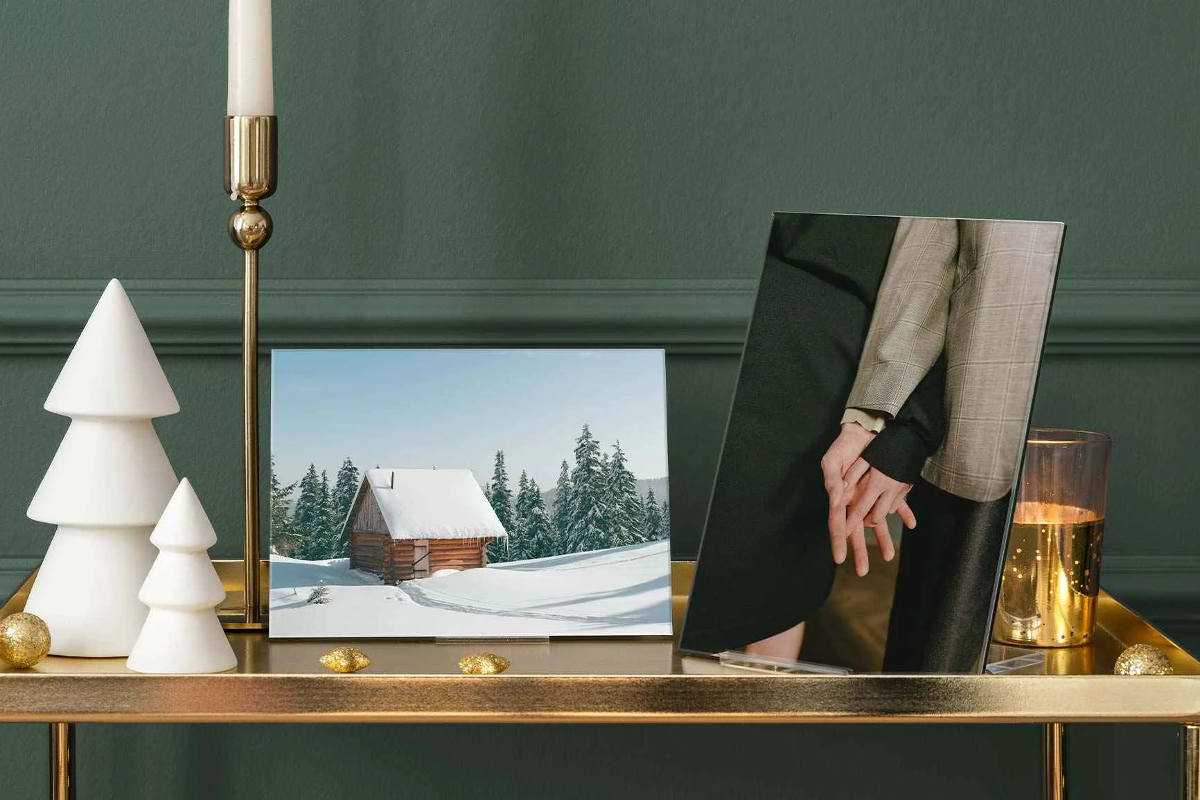 Acrylglas-Fotodisplay mit zwei Fotos: eins zeigt verschneite Hütte im Wald, das andere zwei sich haltende Hände.