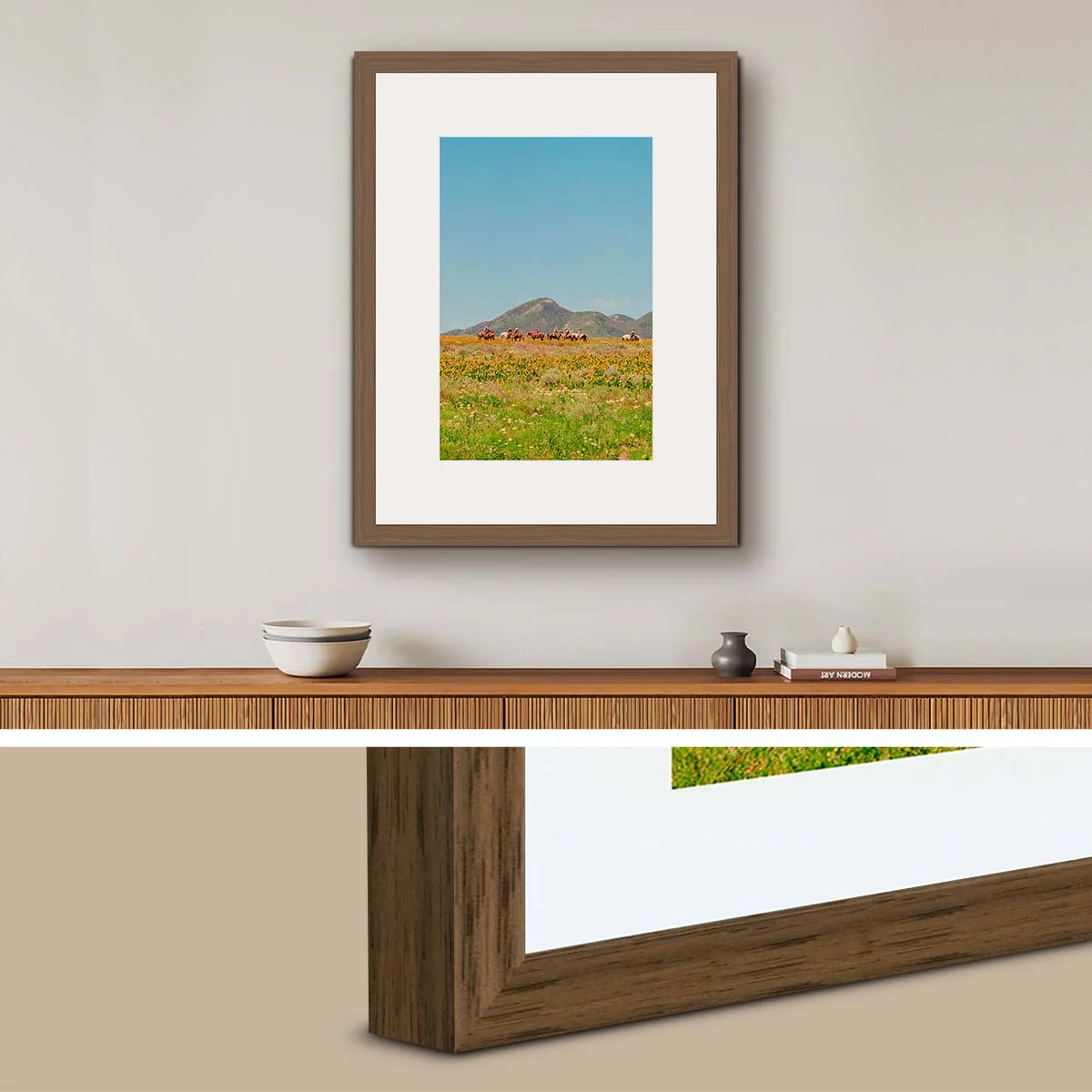 Holzrahmen in Walnussfarbe mit Passepartout um ein Landschaftsfoto mit Berg und Wiese an einer Wand über einem Sideboard, darunter Nahaufnahme vom Rahmen.