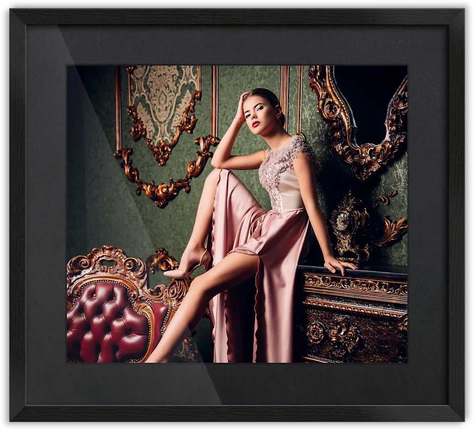 Woman in an elegant pink evening gown sitting on a piece of furniture, passe-partout frame surrounding the photo.