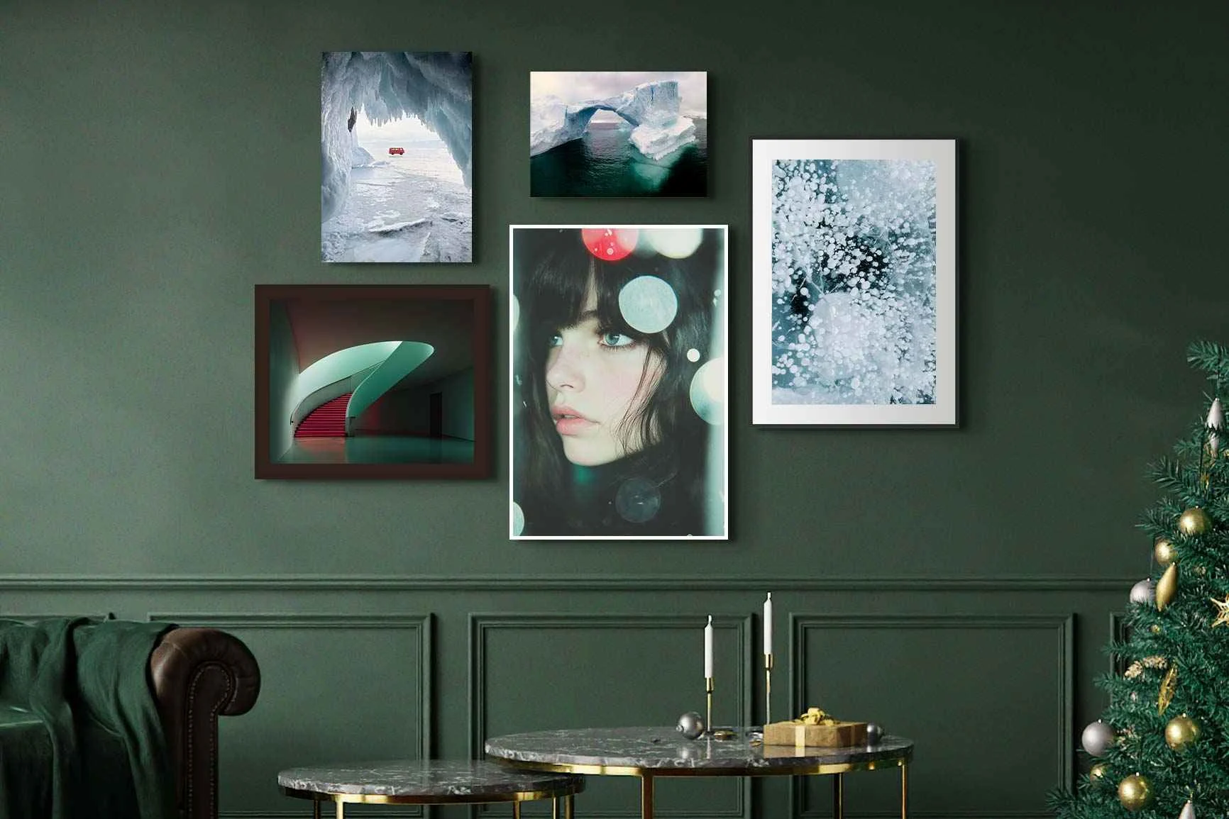 Mehrere abstrakte Motive in Holzrahmen an dunkelgrüner Wand über zwei runden Marmortischen.