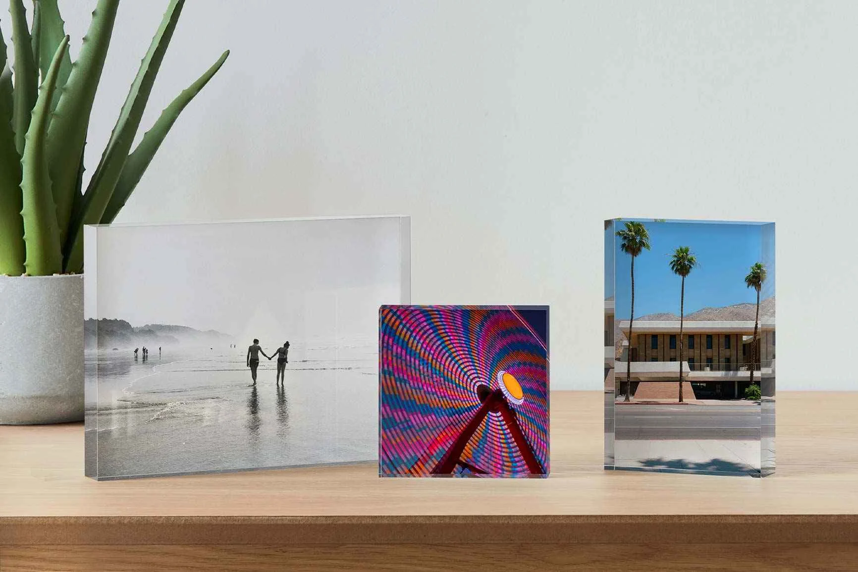 Drei Fotoblöcke aus Acryl auf einem Holztisch mit unterschiedlichen Motiven.