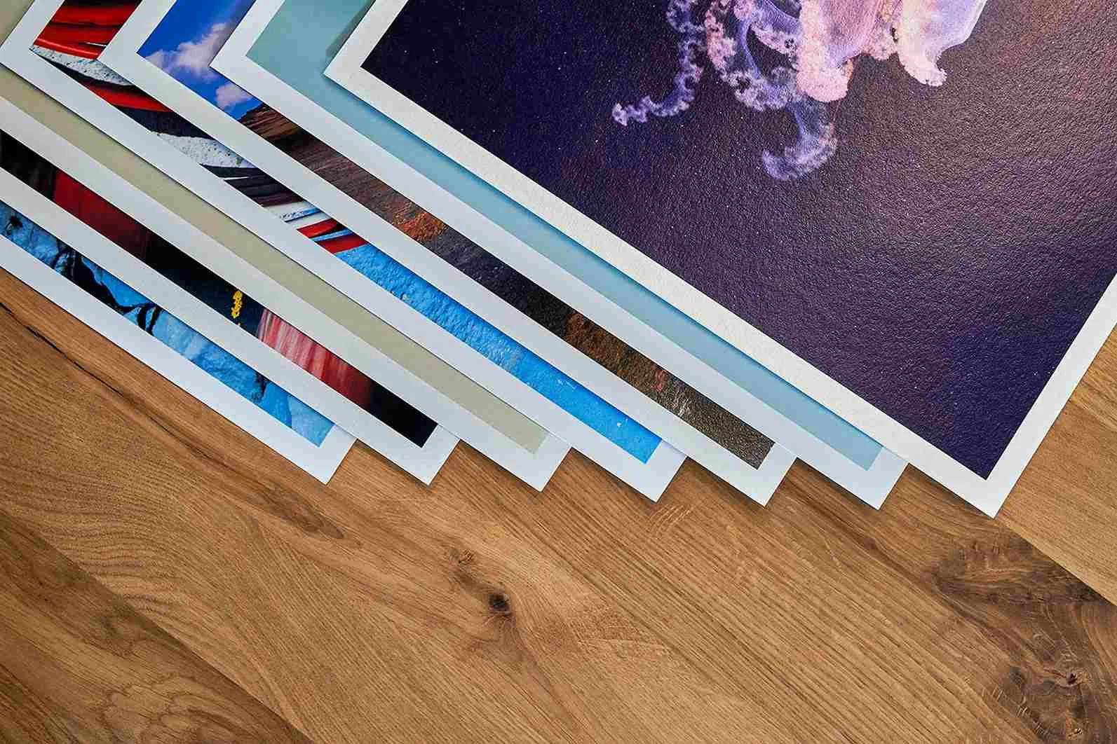 Diverse Fine Art Prints sovrapposte con bordi bianchi su un supporto in legno.