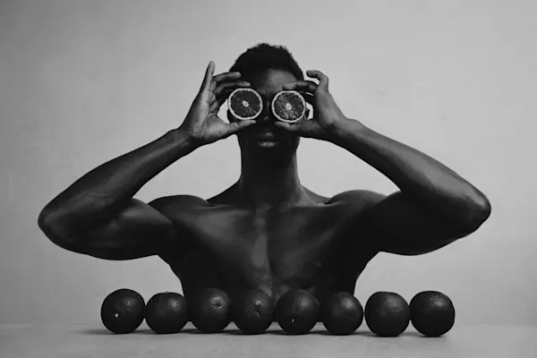 Katrina Dobbermane – Constructed: Schwarz-weiß Aufnahme vom Oberkörper eines Mannes, mit Orangen vor den Augen und den Körper.