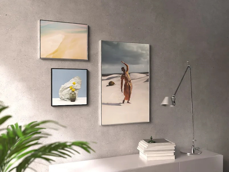 Moderne galerijwand met drie ingelijste kunstwerken op een betonnen muur.