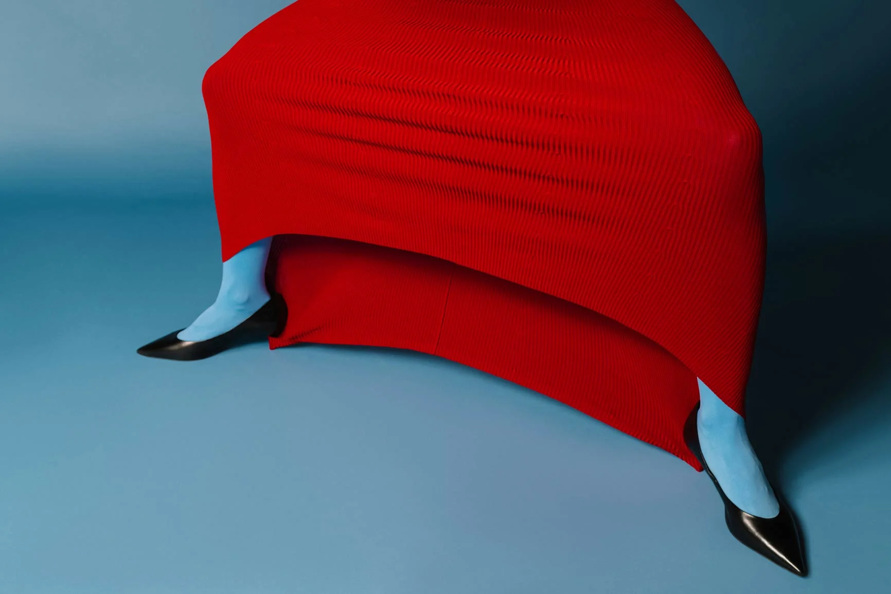 Legs in blue tights and black shoes, partially covered by a red dress, against a blue background.
