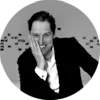 black & white portrait of man smiling to the camera and holding his face with right hand