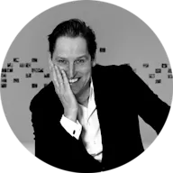 black & white portrait of man smiling to the camera and holding his face with right hand
