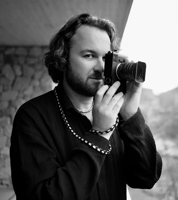 Black-and-white portrait of Alan Schaller holding a camera in front of his face ©Ryota Kohama