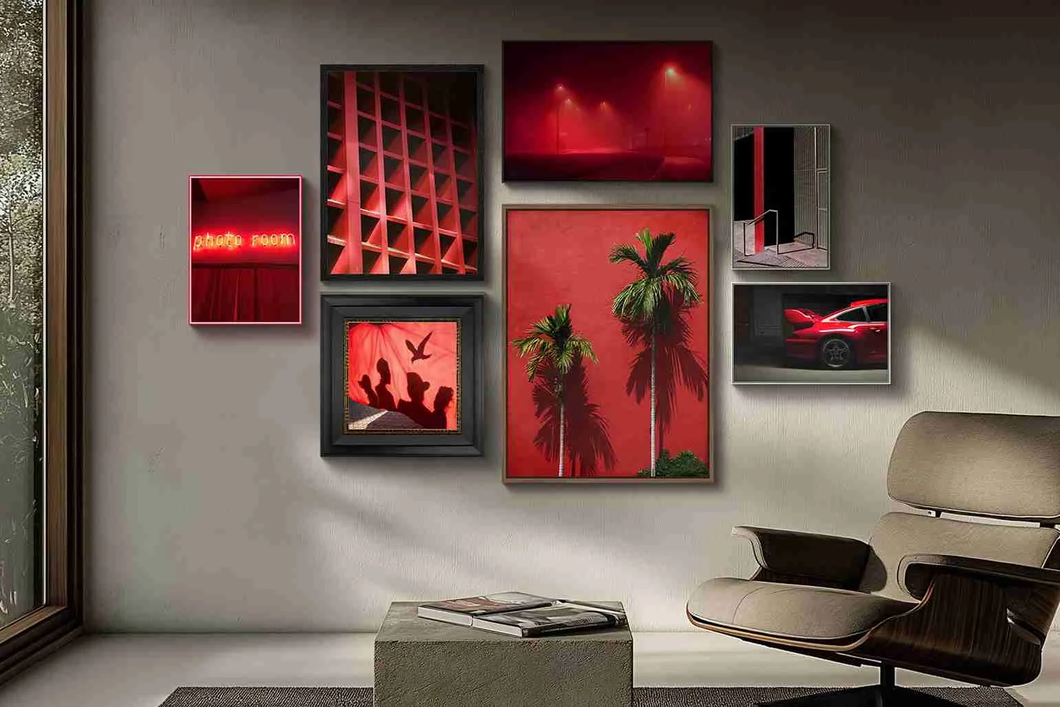 Wand mit sieben gerahmten Bildern in Rot- und Schwarztönen, darunter Palmen, Vögel, Auto und abstrakte Muster.