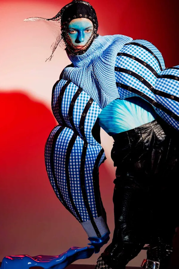 Laura Knipsael – Moltitude: Surreale Fashion-Fotografie mit skulpturaler Kleidung, schwarzer Kopfhaube und blauen Farbakzenten.