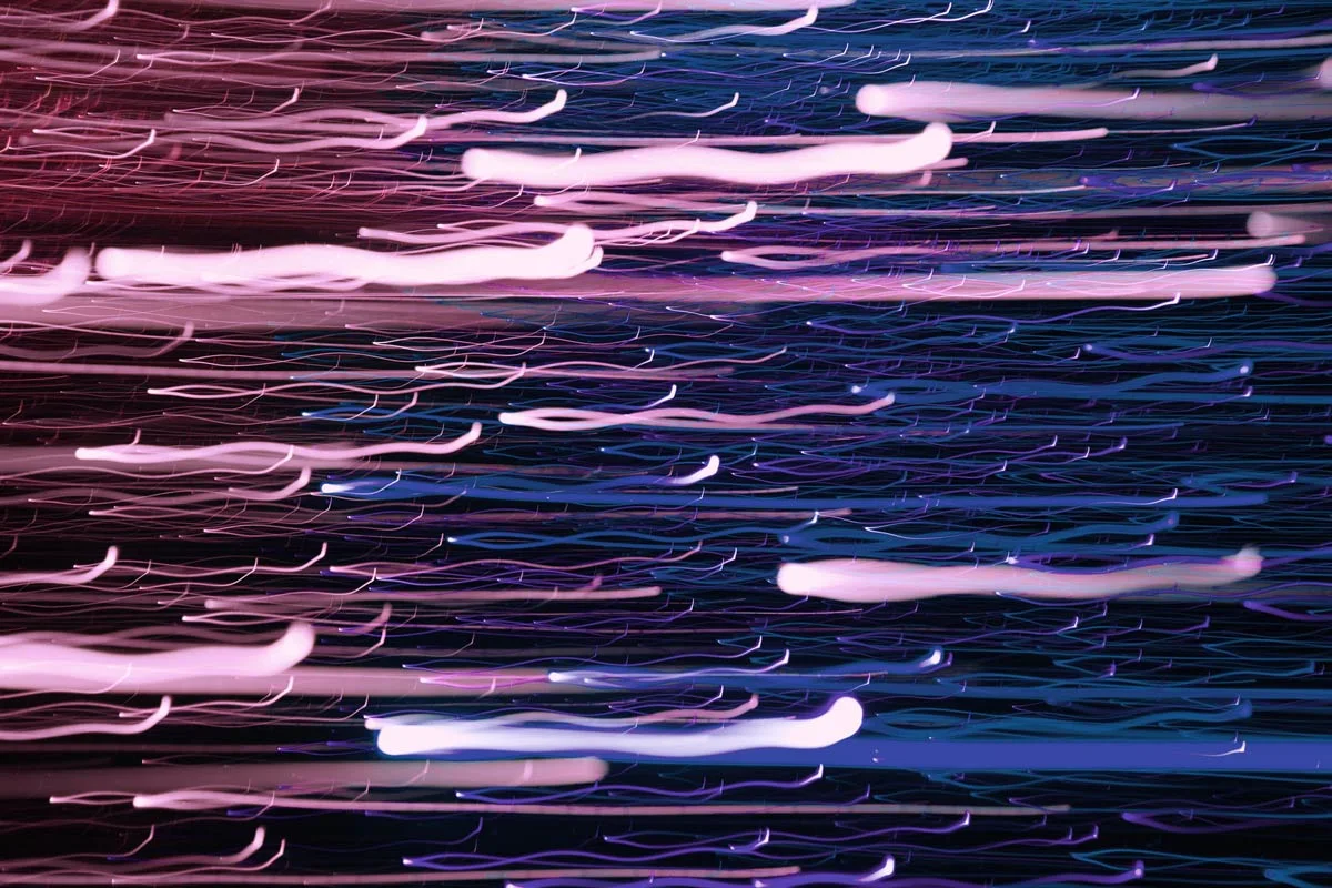 Rayas de luz horizontales difuminadas en rosa, azul y lila sobre un fondo oscuro en exposición prolongada.
